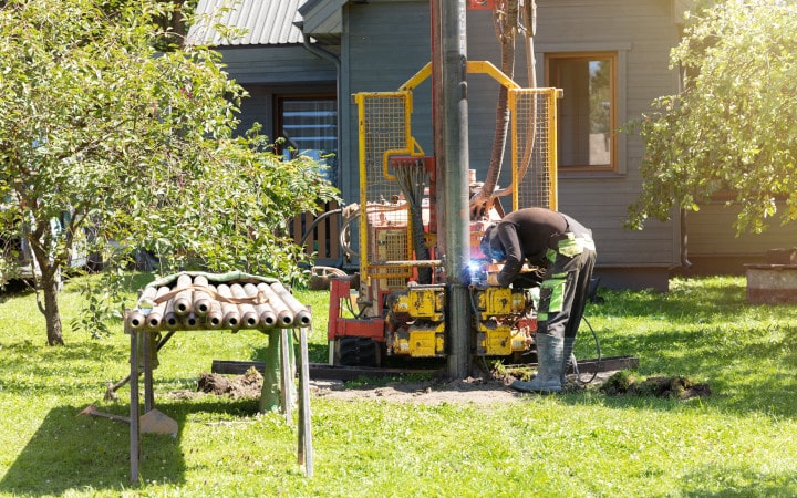 Artisan réalisant le forage d'un puits domestique dans le jardin d'une propriété