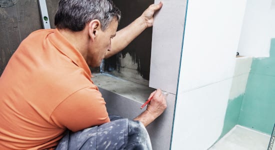 Rénovation d'une douche - Artisan pose un carrelage blanc