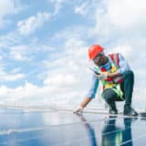 Ingénieurs vérifiant l’installation de panneaux solaires sur le toit d’une maison individuelle