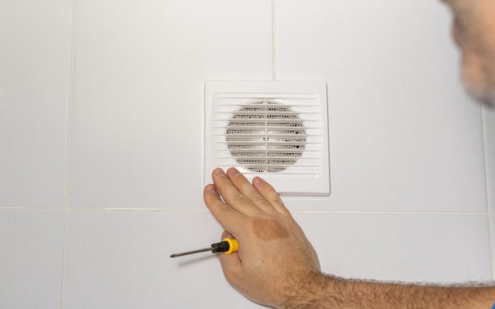 Installation d'une bouche d'aération d'une VMC double flux dans une salle de bain