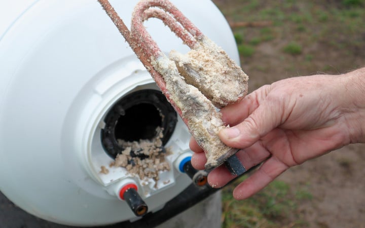 Plombier procède à l’enlèvement du système électrique de chauffe du chauffe-eau afin de procéder à un détartrage