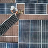 Pose de panneaux solaires sur le toit d'une maison par des artisans