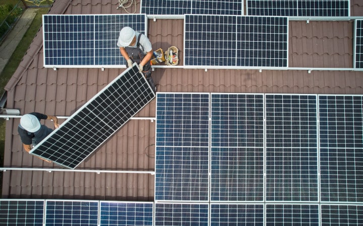 Pose de panneaux solaires sur le toit d'une maison par des artisans