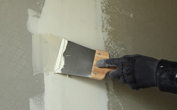 Ratissage d'un mur en Placo à l'aide d'une spatule